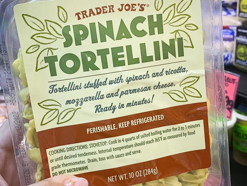 hand holding package of spinach tortellini in trader joes