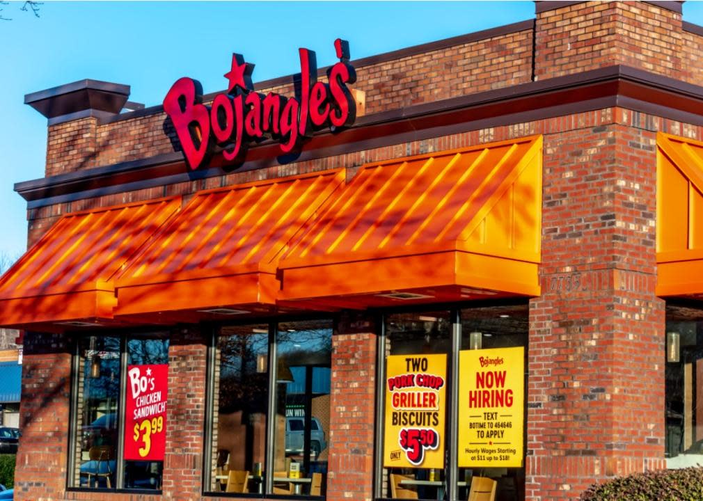 A red brick building with orange slanted overhang and large windows. There is a large sign above the entrance that says Bojangles' in yellow lettering.