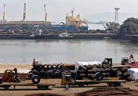 FILE PHOTO: A worker rides his bicycle past steel rims in a dockyard at Mumbai Port Trust in Mumbai November 17, 2014. REUTERS/Shailesh Andrade/File Photo