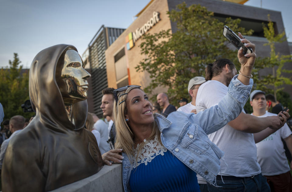 A woman takes a selfie with a newly unveiled statue of the mysterious developer of the Bitcoin digital currency in Budapest, Hungary, Thursday, Sept. 16, 2021. A bronze statue was unveiled in Hungary’s capital on Thursday which its creators say is the first in the world to pay homage to the anonymous creator of the Bitcoin digital currency. Erected in a business park near the Danube River in Budapest, the bust sits atop a stone plinth engraved with the name of Satoshi Nakamoto, the pseudonym of the mysterious developer of Bitcoin whose true identity is unknown. (AP Photo/Bela Szandelszky)