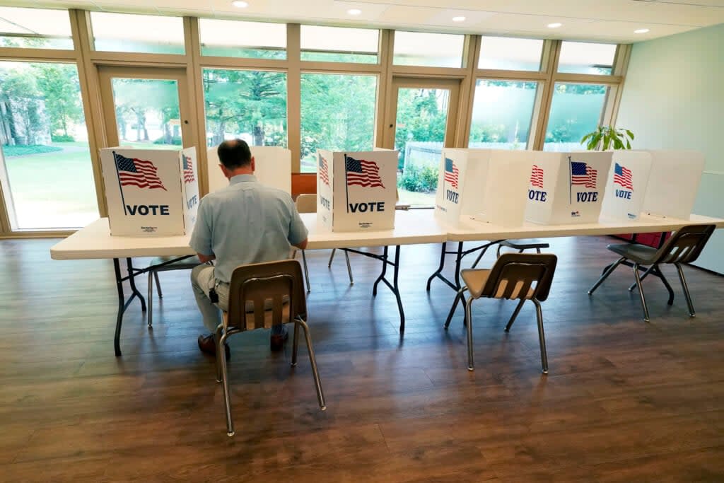 A voter sits alone at a poll kiosk to cast his vote at a Mississippi Second Congressional District Primary election precinct, June 7, 2022, (AP Photo/Rogelio V. Solis, File)