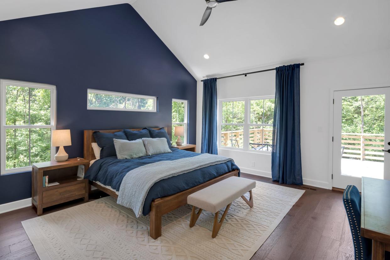 The primary bedroom boasts an accent wall and a door to the deck in this modern farmhouse-style home built by the Eldridge Company in Louisville.