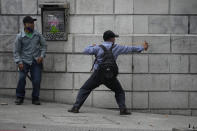 A protester aims a slingshot at police during a protest of veterans demanding that a law be passed that compensates them for having served during the country's civil war, outside the Congress building in Guatemala City, Tuesday, Oct. 19, 2021. (AP Photo/Moises Castillo)