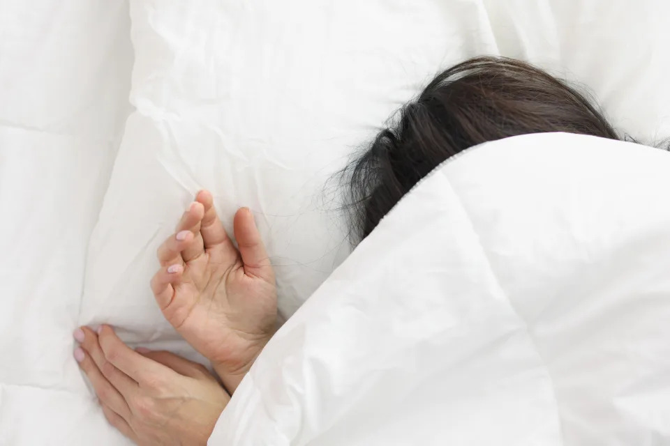 A woman lying under a blanket.