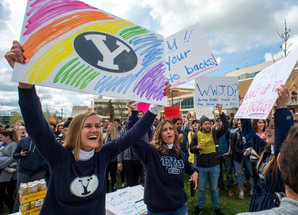 In this April 12, 2019, file photo, Sidney Draughon holds a sign as she takes part in a protest in Provo, Utah, against how the Brigham Young University Honor Code Office investigates and disciplines students. Brigham Young University in Utah has revised its strict code of conduct to strip a rule that banned any behavior that reflected "homosexual feelings."