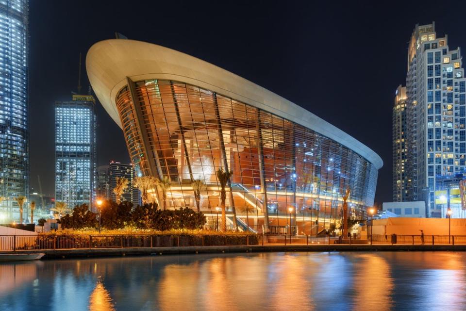 The Dubai Opera House lit up at night overlooking the water