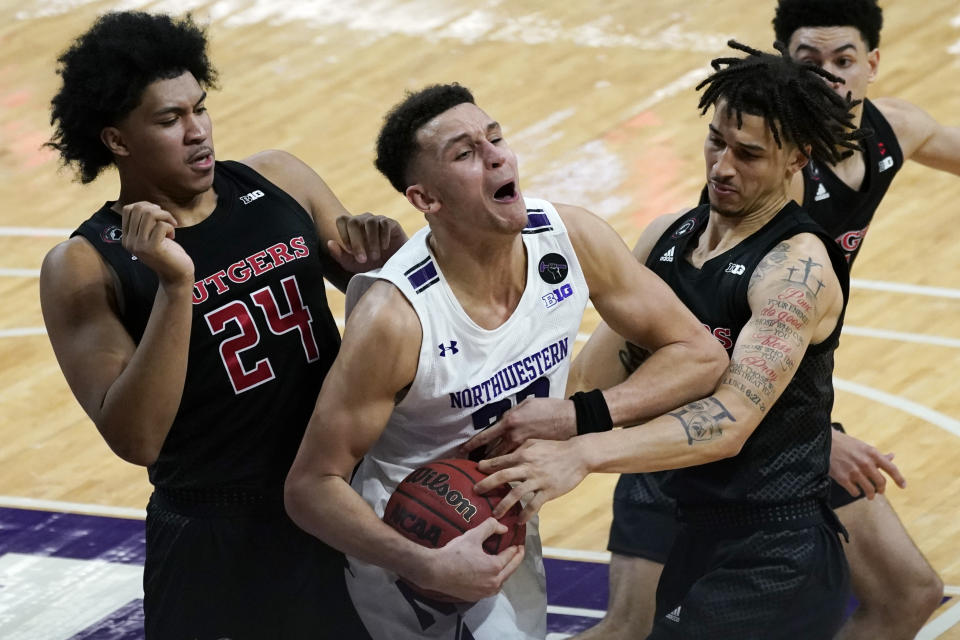 Northwestern forward Pete Nance, center, reacts as he battles for a rebound against Rutgers guard/forward Ron Harper Jr., left, and guard Caleb McConnell during the second half of an NCAA college basketball game in Evanston, Ill., Sunday, Jan. 31, 2021. (AP Photo/Nam Y. Huh)