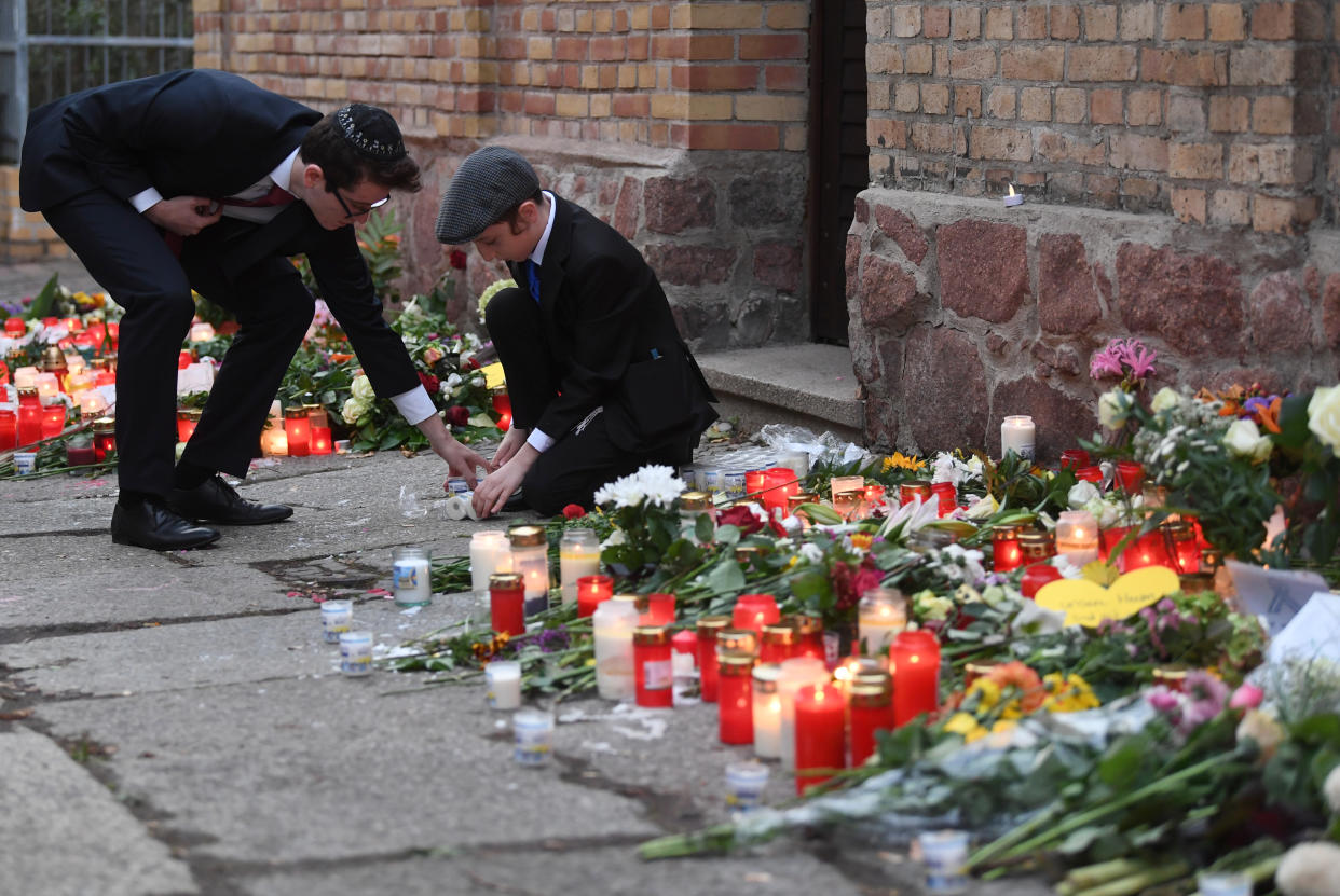 11 October 2019, Saxony-Anhalt, Halle/Saale: Two men lay flowers and candles on the wall of the synagogue. On 09.10.2019, two people were shot dead during an attack by an extreme right-wing perpetrator in front of a synagogue in Halle. Photo: Hendrik Schmidt/dpa (Photo by Hendrik Schmidt/picture alliance via Getty Images)