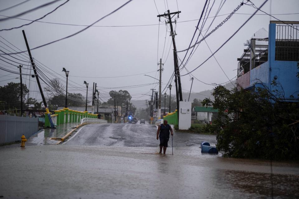 A man wades through a flooded street after Hurricane Fiona affected the area in Yauco, Puerto Rico (Reuters)