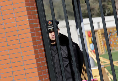 A security guard is pictured through the gate at the kindergarten run by pre-school operator RYB Education Inc being investigated by China's police, in Beijing, China November 24, 2017. REUTERS/Jason Lee