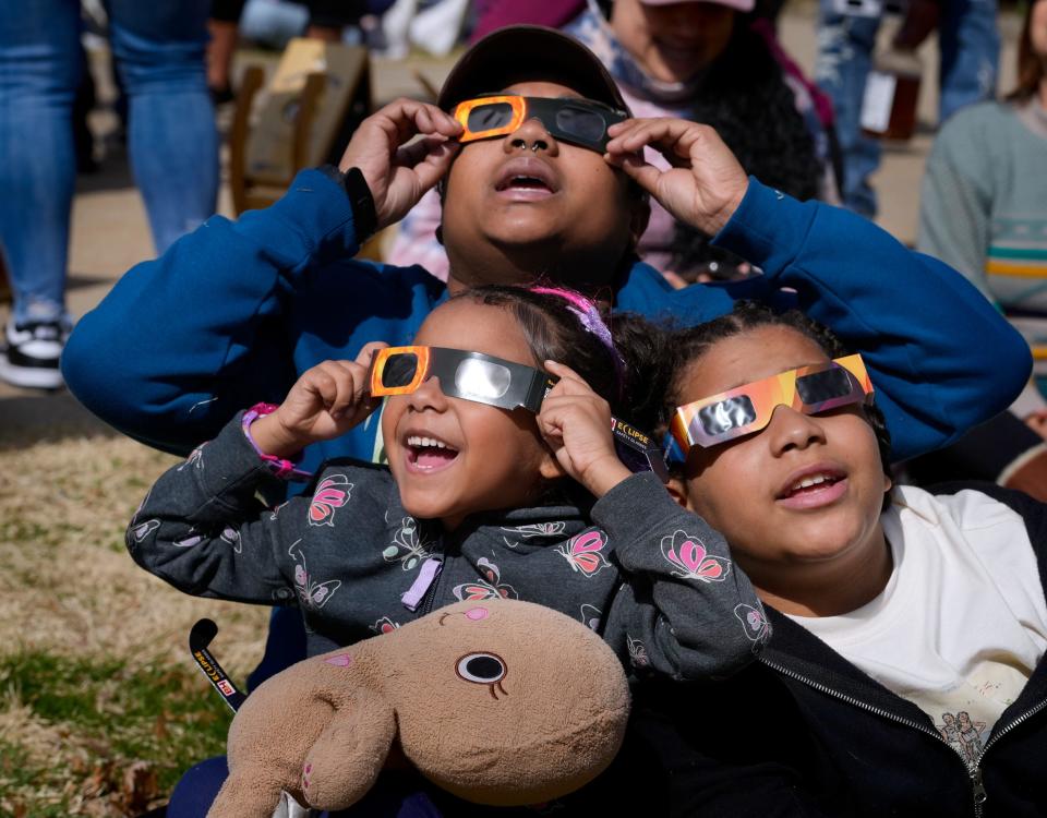 Iolanda Monteiro and her children, 5-year-old-Soleil and 13-year-old Neyomiah, stare in awe at the eclipse on Monday from the front lawn of the Museum of Natural History and Planetarium in Roger Williams Park, Providence. Museum Director Renee Gamba said the museum ordered 2,000 eclipse glasses for viewers.