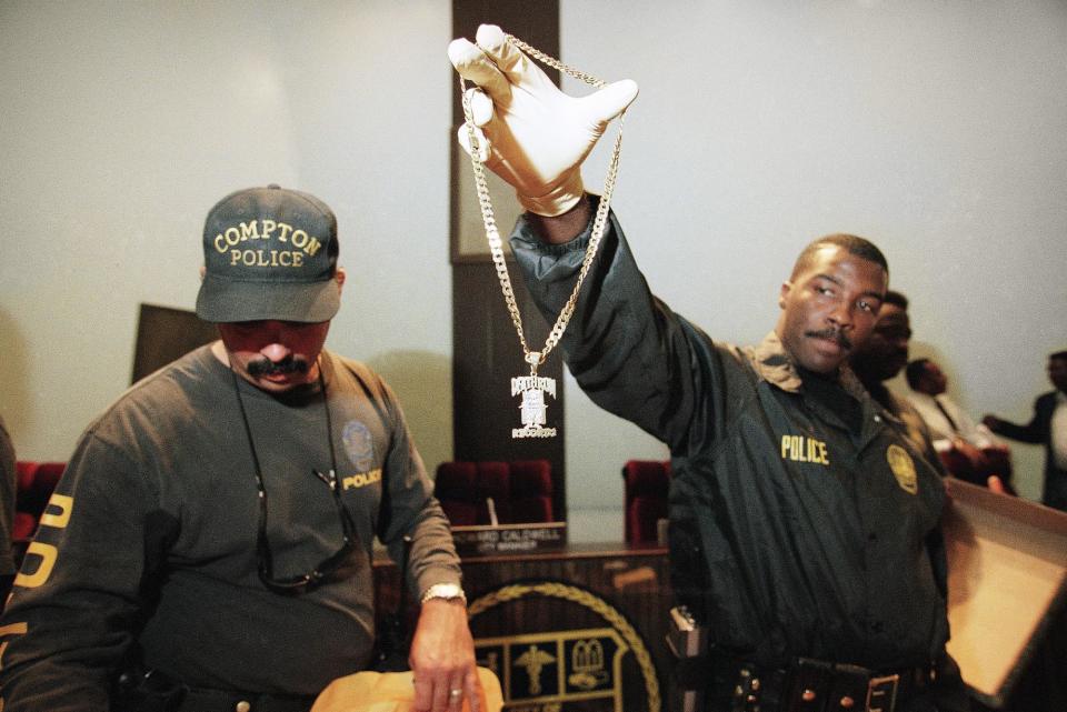 Compton Police officer Anthony Easter holds up a necklace with the ìDeath Row Recordsî logo belonging to one of the suspects arrested for murder or related charges for 12 shootings that occurred in Compton since September 7, during staged raids by nine federal, state and local law enforcement agencies on Wednesday, Oct. 2, 1996. Compton Police Department investigators stated that the motives for some of the shootings may have been in retaliation for the shooting of rap artist Tupac Shakur in Las Vegas on Sept. 7, 1996. (AP Photo/Michael Caulfield)