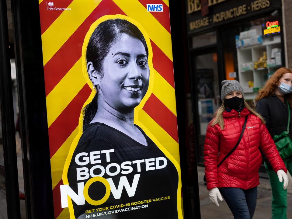 Members of the public walk past a sign on Shaftesbury Avenue urging people to get their Covid booster jabs (Getty)