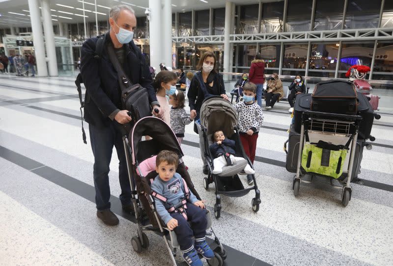 Dr. Fouad Boulos, Associate Professor of Clinical Pathology and Laboratory Medicine at the American University of Beirut (AUB) pushes a baby cart near his wife and children, at Beirut International airport