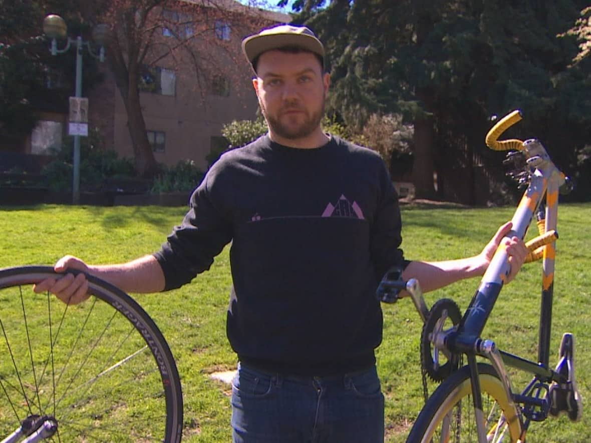 Ben Bolliger holds the pieces of the bike he was riding when he was struck by a car in 2021. (CBC - image credit)