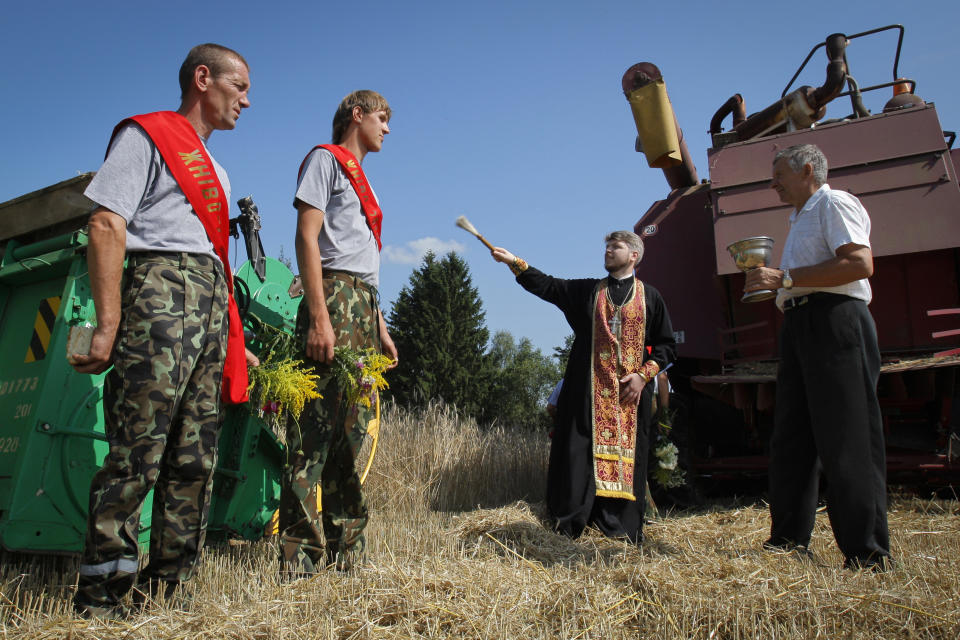 FILE - An Orthodox priest blesses drivers of combine harvesters during in the village of Lenino, some 60 kilometers ( 37,5 miles) southwest of Minsk, Belarus, on Tuesday, July 20, 2010. Authoritarian President Alexander Lukashenko, who has ruled Belarus for nearly 30 years and describes himself as an "Orthodox atheist," lashed out at dissident clergy during the 2020 protests, accusing them of fueling the unrest that was sparked by his reelection in a vote that was widely seen at home and abroad as rigged. He urged them to "do their jobs" and stay out of politics. (AP Photo, File)