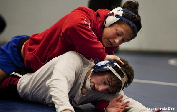 Men in wrestling tights and wrestlers holds the foot of a wrestler