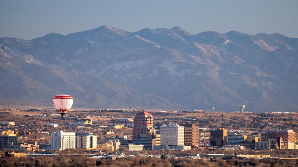 A hot air balloon floats over the skyscrapers of downtown Albuquerque, New Mexico.