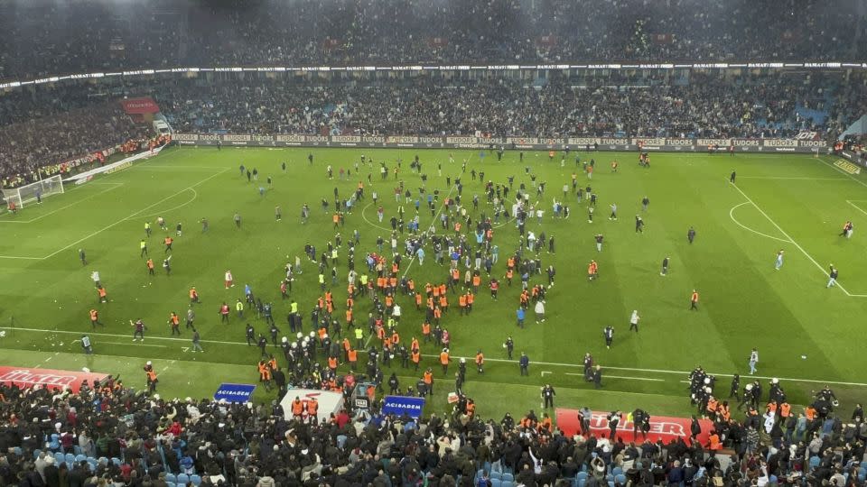 Trabzonspor fans invade the pitch and clash with Fenerbahçe players and security staff after the match. - Ihlas News Agency/Reuters
