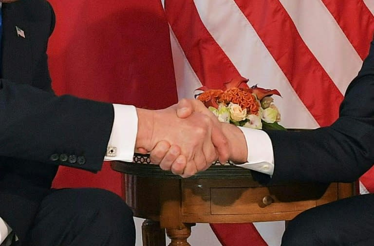 US President Donald Trump (L) and French President Emmanuel Macron shake hands ahead of a working lunch in brussels