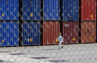 A worker walks between shipping containers at a port in Tokyo, Japan, March 22, 2017. REUTERS/Issei Kato