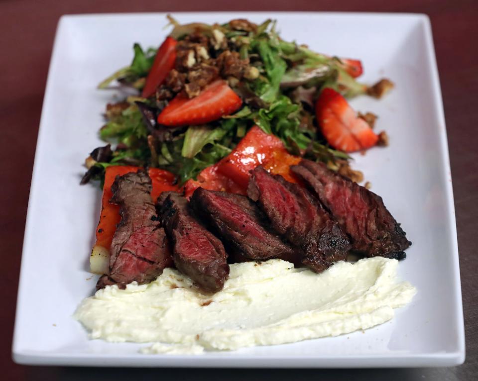 The Eye Opener's watermelon steak salad, a mix of greens, candied pecans, strawberries and bruleed watermelon, is served with grilled hanger steak and feta mousse.