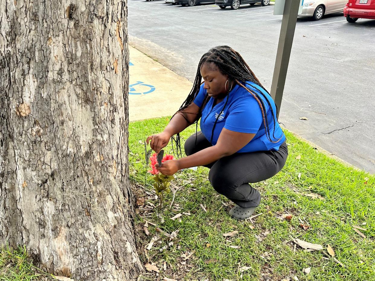 LaToya Jackson places a flower arrangement in the ground at Mission Hills Apartments on July 24, 2023. Her cousins, Qulera Allen, 29, and Kernishion Charleston, 37, were shot and killed outside Allen's apartment on July 23, 2023.