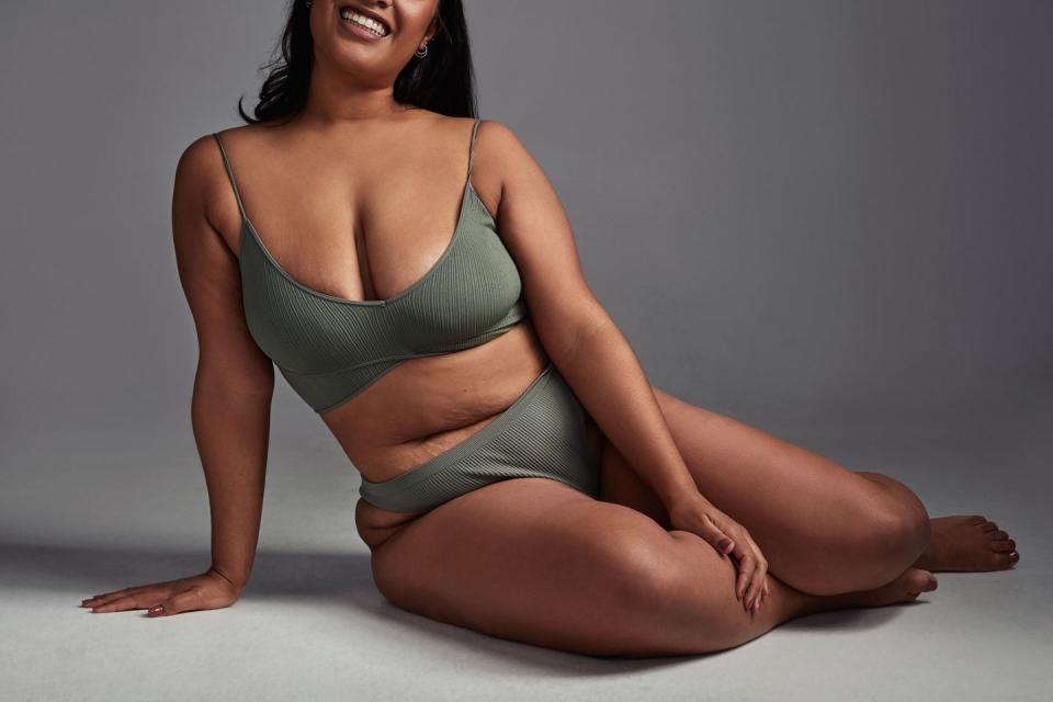 shot of a young woman posing in her underwear against a grey background