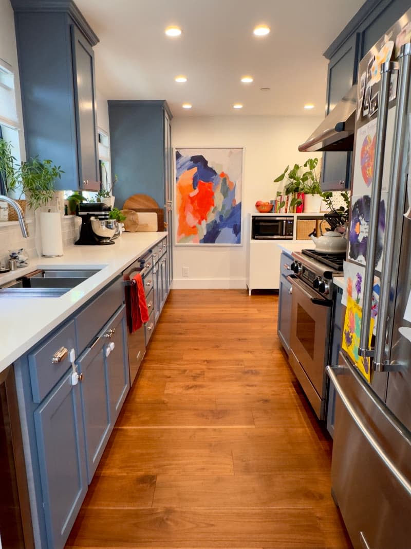 galley kitchen with blue cabinets and colorful modern art on wall