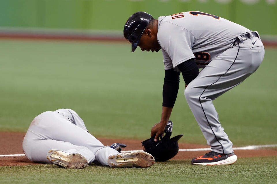 Detroit Tigers' Derek Hill lays on the field as first base coach Kimera Bartee leans over during the fifth inning of a baseball game against the Tampa Bay Rays Saturday, Sept. 18, 2021, in St. Petersburg, Fla. (AP Photo/Scott Audette)