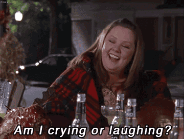 Melissa McCarthy at an outdoor table, smiling and laughing with the text "Am I crying or laughing?" in front of her