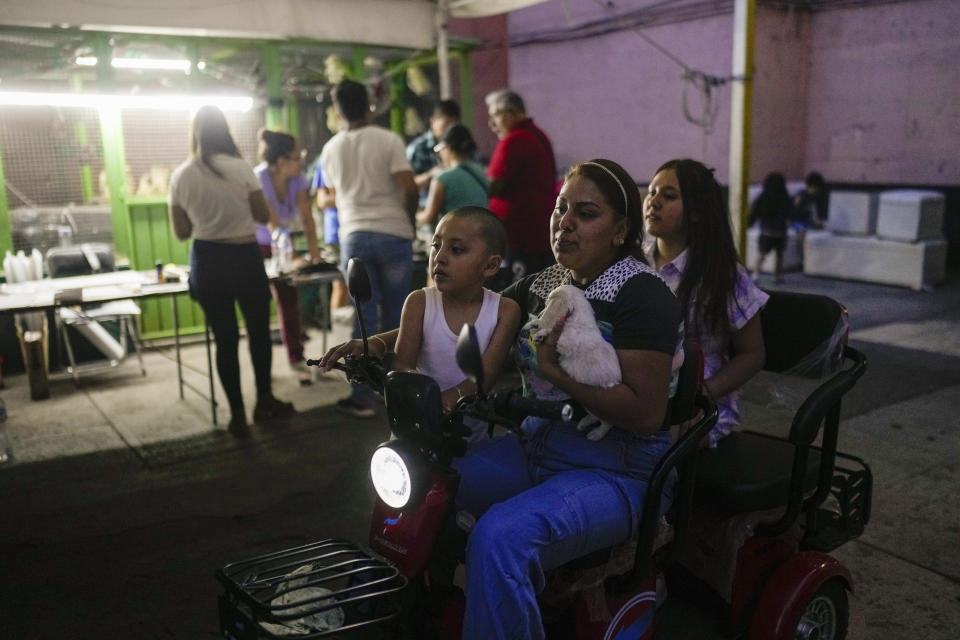 A family on a scooter rides past electoral officials and poll watchers as they count votes after the polls closed during general elections in Mexico City, Sunday, June 2, 2024. (AP Photo/Matias Delacroix)