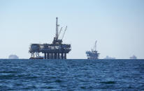 Dozens of cargo vessels are seen anchored offshore, sharing space with about a half dozen oil platforms, before heading into the Los Angeles-Long Beach port, Tuesday, Oct. 5, 2021. (AP Photo/Eugene Garcia)