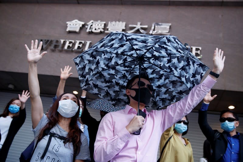 Office workers shout slogans as they attend a lunchtime anti-government protest in the Central district of Hong Kong