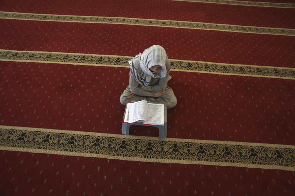 A boy reads holy book of Quran ahead of the Muslim fasting month of Ramadan, in Peshawar, Pakistan, Friday, April 24, 2020. Muslims all around the world are trying to work out how to maintain the many cherished rituals of Islam's holiest month. (AP Photo/Muhammad Sajjad)