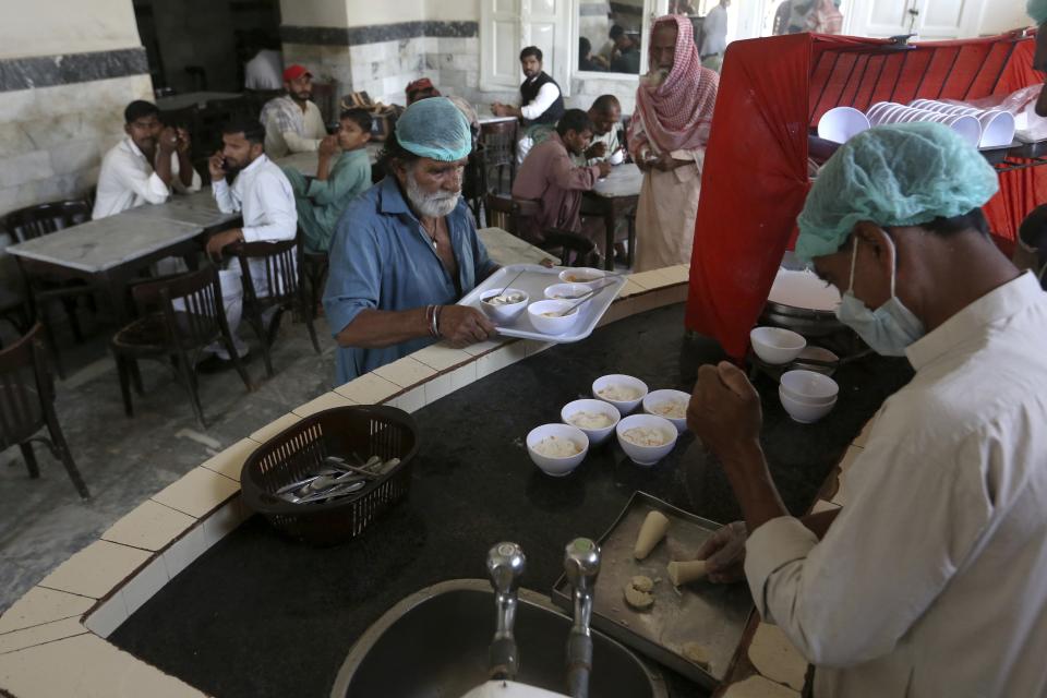 A worker prepares falooda, an ice-cream-based dessert with noodles, for customers at a famous 67-year-old sweet shop run by a Hindu businessman, in Shikarpur, Pakistan, Wednesday, Oct. 26, 2022. The landscape of Pakistan, and Sindh in particular, retains their imprint. It has temples, although their numbers have plummeted, businesses, education and healthcare institutions, many established before the country was created in 1947. These places are part of Pakistan's heritage, even as Hindus are forced into the shadows. (AP Photo/Fareed Khan)