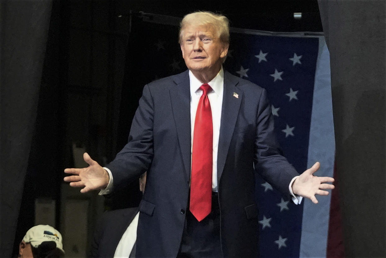 Former President Donald Trump gestures during a campaign rally, with his arms open and his palms facing up.