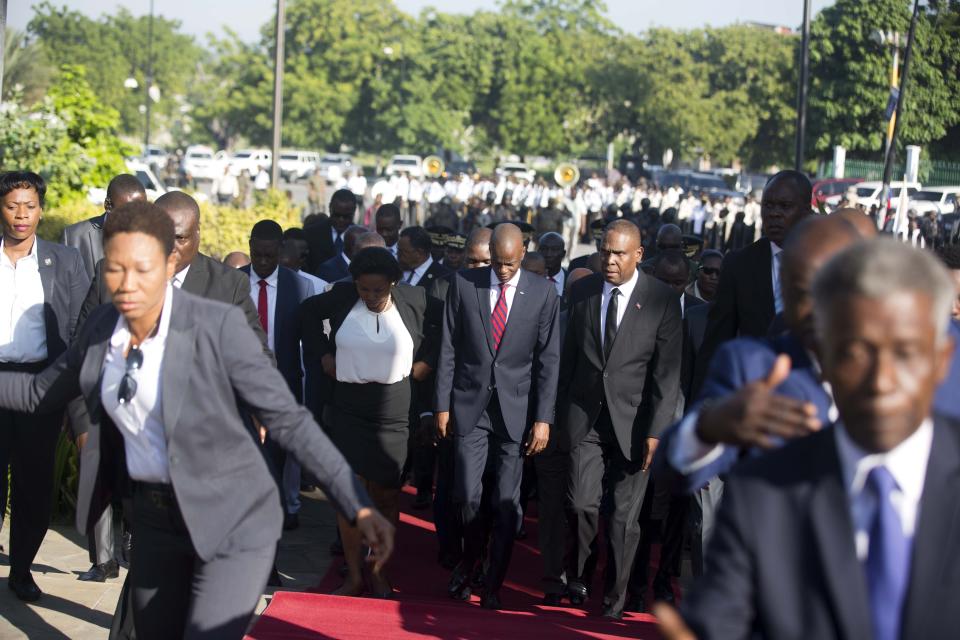 El presidente haitiano Jovenel Moïse, al centro, llega con la primera dama Martine, izquierda, y el primer ministro Jean-Henry Ceant, derecha, a un acto en el 215to aniversario de la batalla de Vertieres, el último paso de los haitianos para obtener su independencia de Francia, en Puerto Príncipe, el domingo 18 de noviembre de 2018. ( AP Foto/Dieu Nalio Chery)