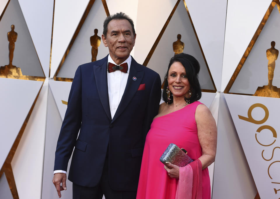 FILE - This March 4, 2018 file photo shows Wes Studi, left, and Maura Dhu at the Oscars in Los Angeles. Studi will become the first Native American actor to receive an Oscar Sunday night at the Governors Awards. (Photo by Jordan Strauss/Invision/AP, File)