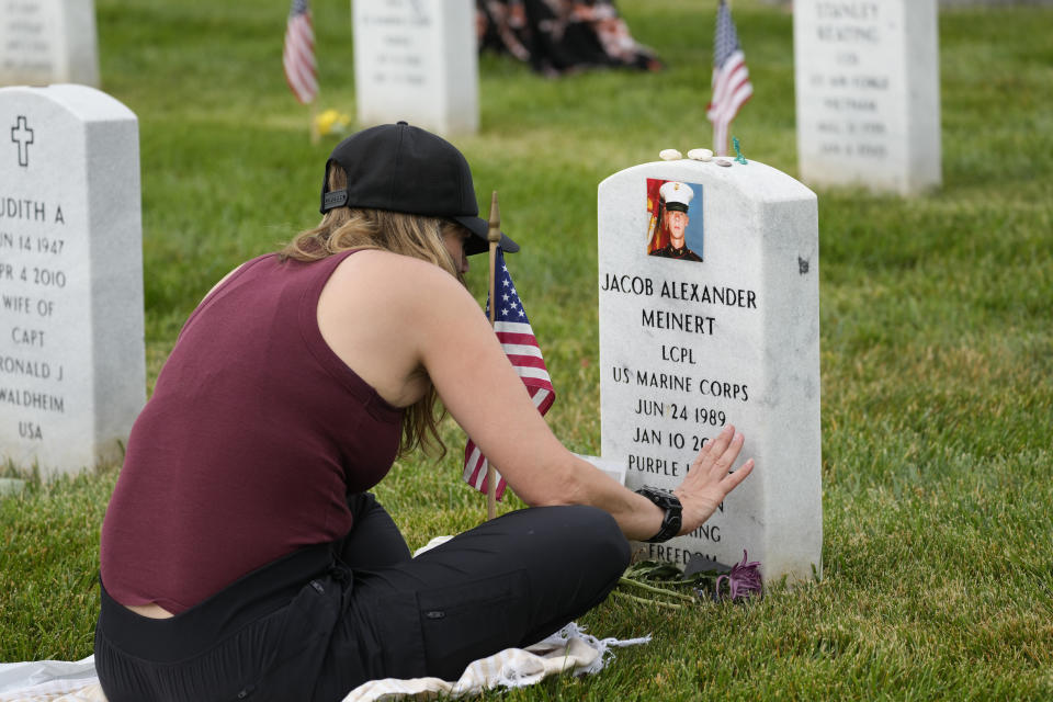 Krista Meinert touches the headstone of her son U.S. Marine Corps Lance Cpl. Jacob Alexander Meinert as she visits his grave in Section 60 at Arlington National Cemetery on Memorial Day, Monday, May 29, 2023, in Arlington, Va. (AP Photo/Alex Brandon)