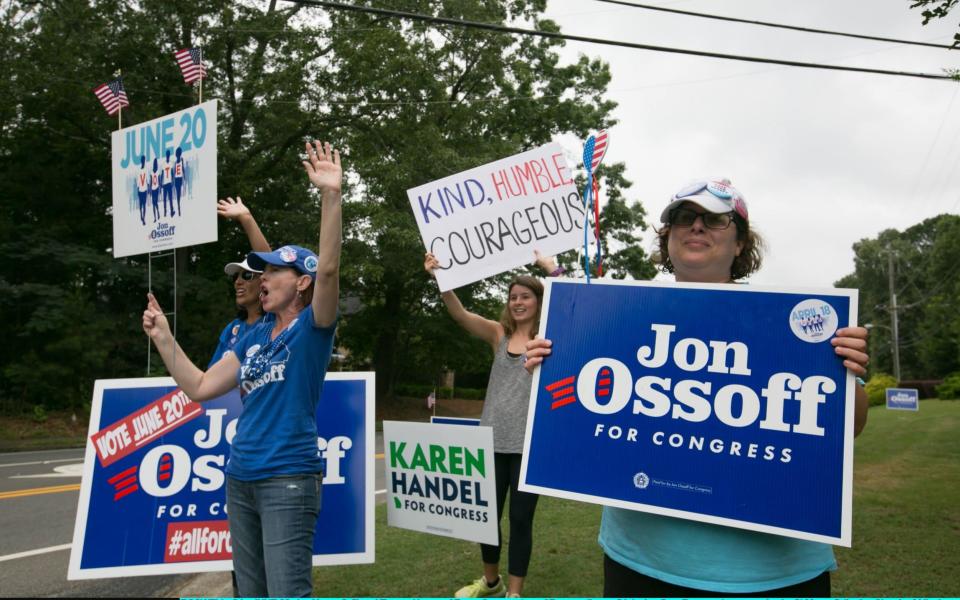 Jan Yanes (left) and Tammy Harper of Roswell, supporters of Democratic candidate Jon Ossoff, wave at cars passing by St. Mary's Orthodox Church of Atlanta on June 20, 2017 in Roswell, Georgia - Credit: Getty