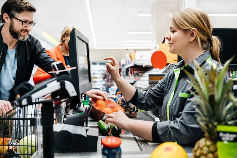 Supermarket employee checks out customers