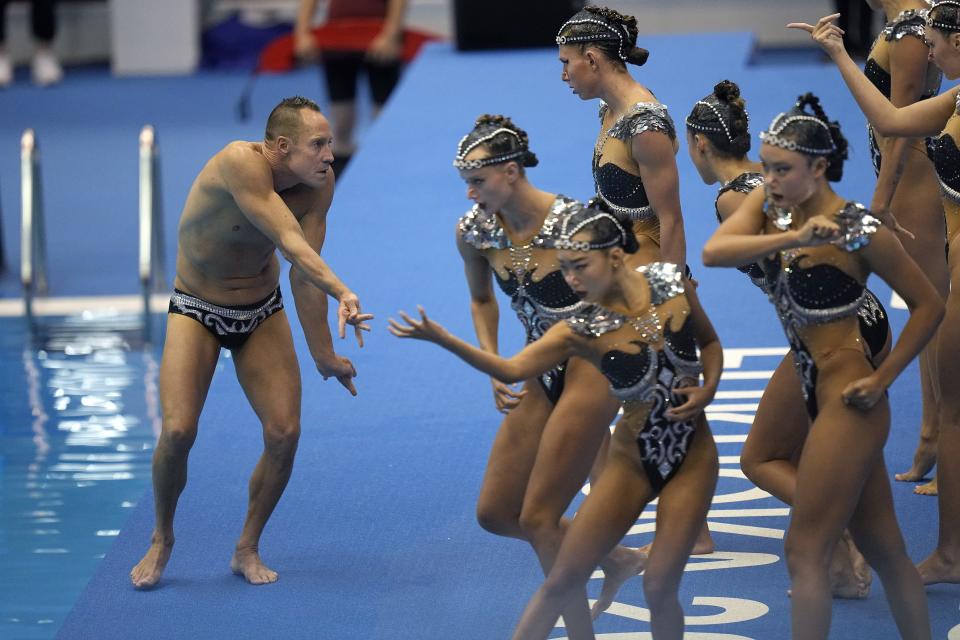 Bill May, left, leads the United States team out to compete in the team acrobatic of artistic swimming at the World Swimming Championships in Fukuoka, Japan, Saturday, July 15, 2023. Largely unnoticed by the general public, men have been participating in artistic swimming, formerly known as synchronized swimming, for decades. (AP Photo/David J. Phillip)