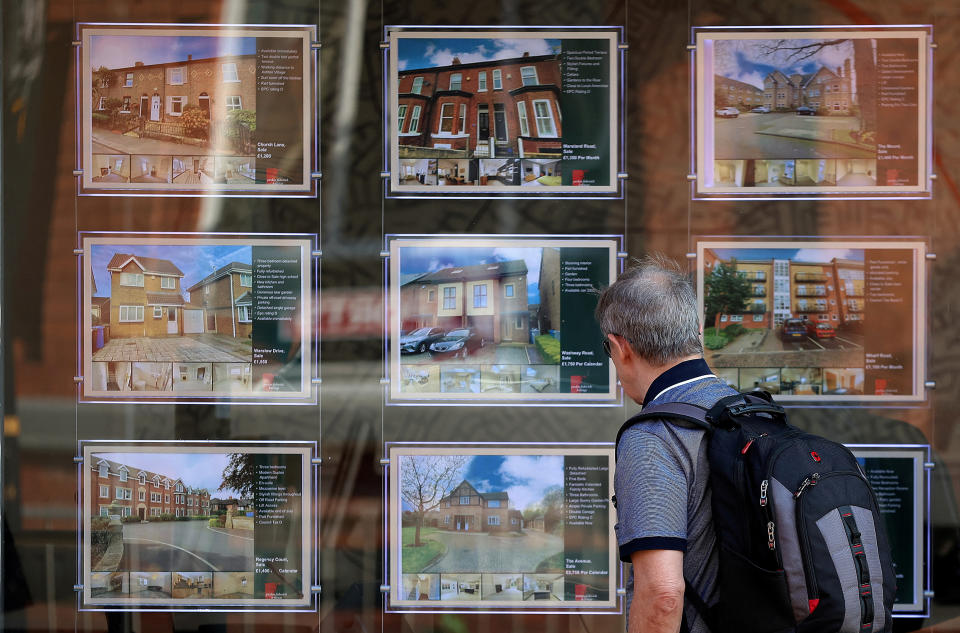 Bir adam emlakçının vitrinindeki satılık evlere bakıyor.  (Fotoğraf: Phil Noble, Reuters)