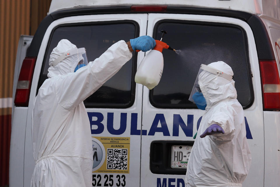 Ambulance workers take turns spraying each other with disinfectant after delivering a patient to the COVID-19 triage unit at Mexico General Hospital in Mexico City, Monday, May 25, 2020. Authorities have predicted that coronavirus cases in the city would peak in May, with reopening measures currently slated for mid-June. (AP Photo/Rebecca Blackwell)