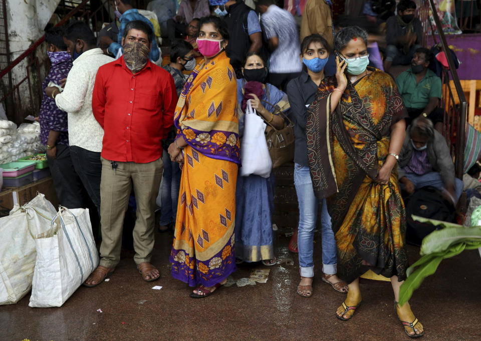 People wait to leave as it rains after shopping at a wholesale flower market ahead of the Hindu festival of Dussehra, in Bengaluru, India, Friday, Oct. 23, 2020. Weeks after India fully opened up from a harsh lockdown and began to modestly turn a corner by cutting new infections by near half, a Hindu festival season is raising fears that the disease could spoil the hard-won gains. Health experts worry the festivals can set off a whole new cascade of infections, further testing and straining India’s battered health care system. (AP Photo/Aijaz Rahi)