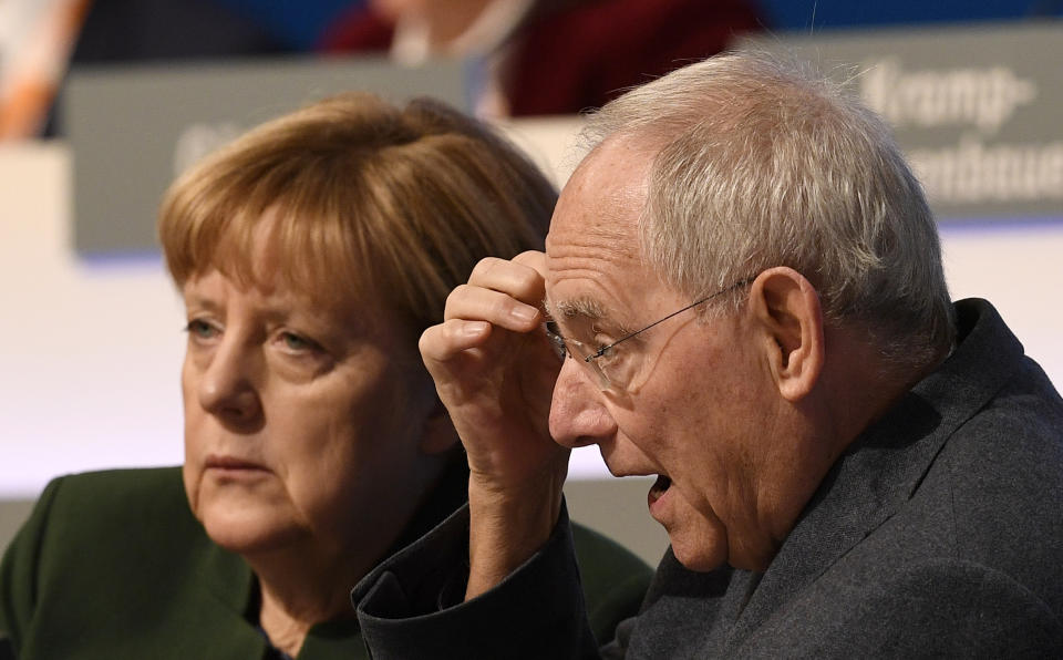 FILE - German Chancellor Angela Merkel, left, and German Finance Minister Wolfgang Schaeuble sit on the podium at the general party conference of the Christian Democratic Union, CDU, in Essen, Germany, Wednesday, Dec. 7, 2016. Wolfgang Schaeuble, who helped negotiate German reunification in 1990 and as finance minister was a central figure in the austerity-heavy effort to drag Europe out of its debt crisis more than two decades later, has died on Tuesday, Dec. 26, 2023. He was 81. (AP Photo/Martin Meissner, File)