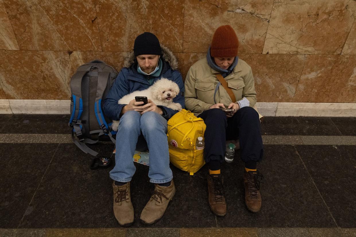 People shelter with their dog in a subway station before a curfew comes into effect on Feb. 24, 2022, in Kyiv, Ukraine. Overnight, Russia began a large-scale attack on Ukraine, with explosions reported in multiple cities and far outside the restive eastern regions held by Russian-backed rebels.