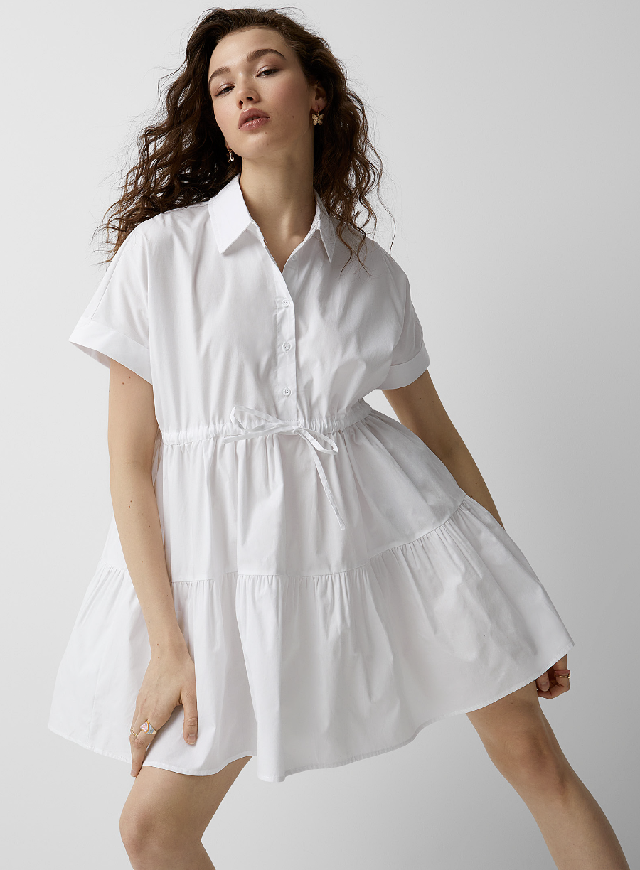model with red curly hair wearing white Fitted waist poplin babydoll dress (photo via Simons)