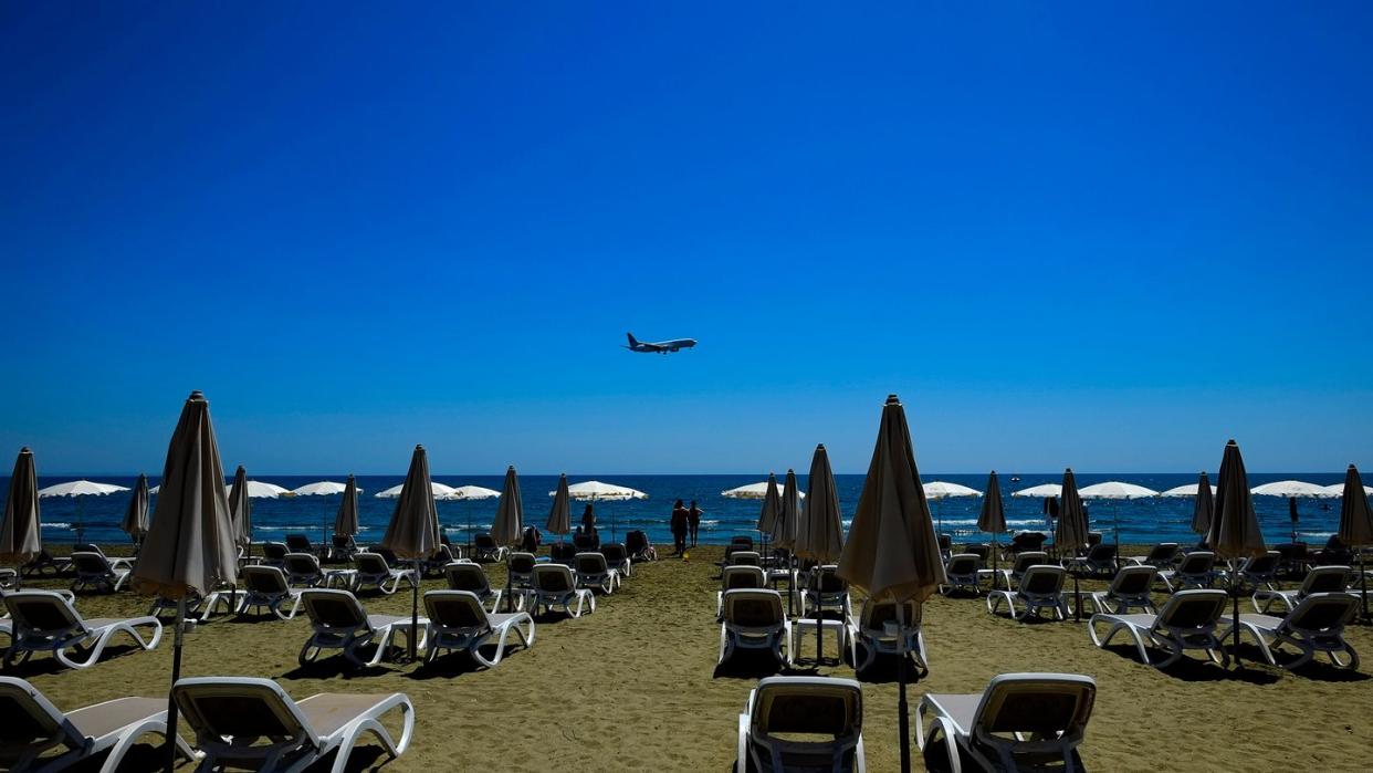 Einige Menschen besuchen den Makenzi-Strand, während sich im Hintergrund ein Flugzeug auf die Landung am internationalen Flughafen Larnaka vorbereitet. Zypern ist nun auch als Risikogebiet eingestuft worden.